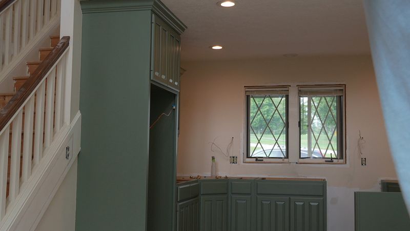 Green built-in cabinetry with a window beyond