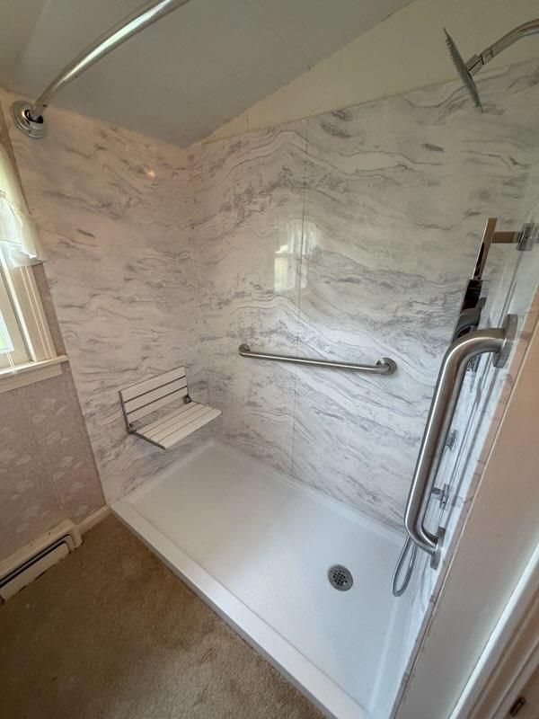 Walk-in shower with a grab bar and low white base