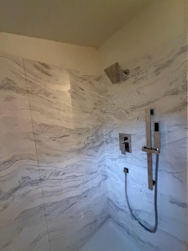 Marble-pattern shower wall with dark shower fixtures