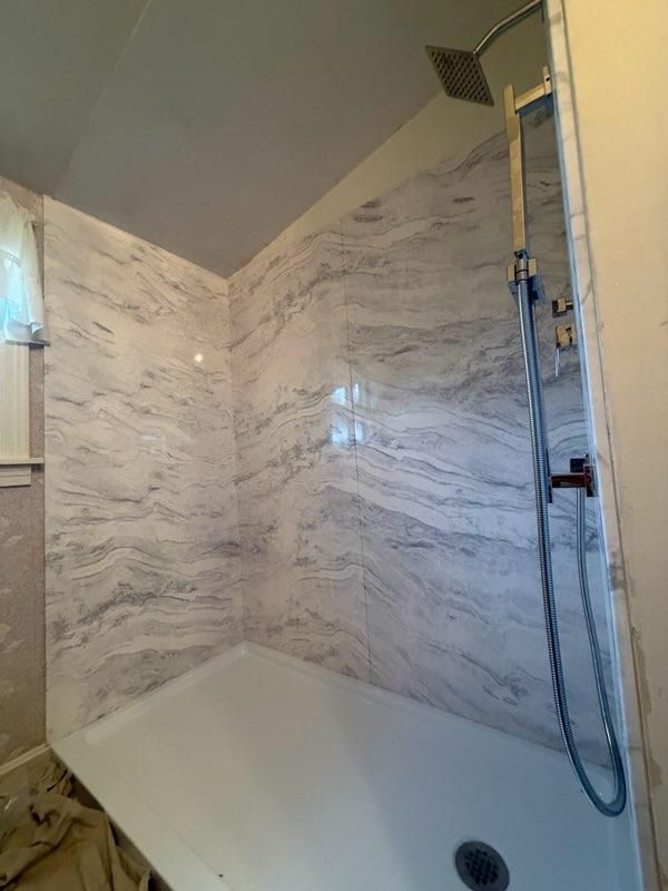 Walk-in shower with marble-pattern wall panels and a handheld shower