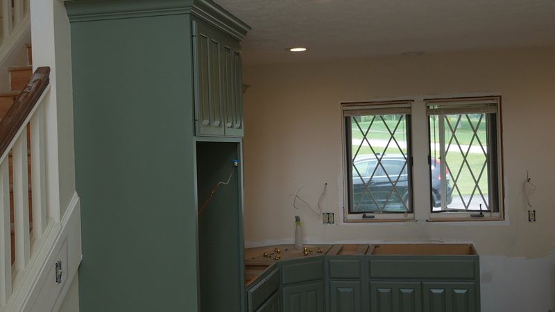 Muted green built-in cabinetry beside a dining area